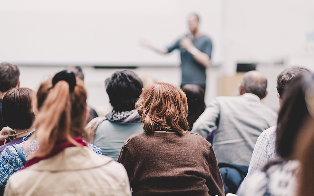 Audience attending a scientific lecture or workshop with a speaker presenting at the front of the room