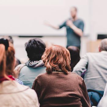 Audience attending a scientific lecture or workshop with a speaker presenting at the front of the room.